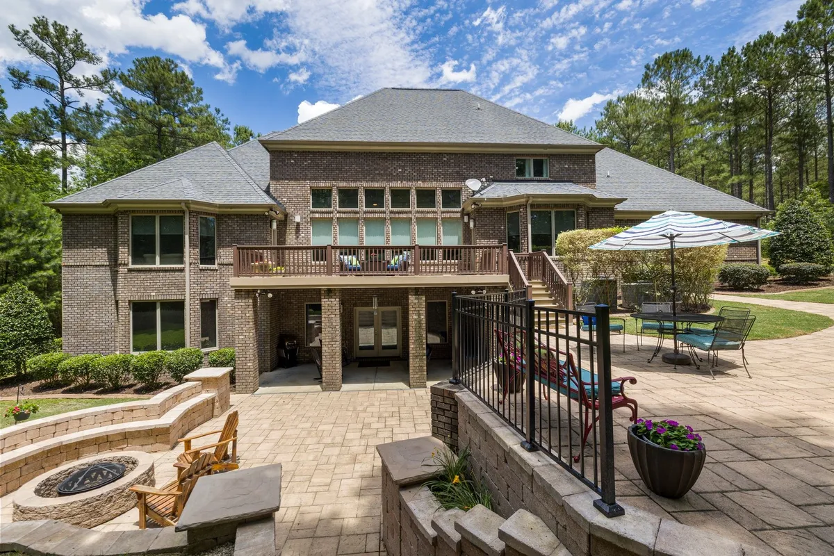 Luxury brick house with a spacious terrace, fire pit, and a beautifully maintained garden, ideal for outdoor living.