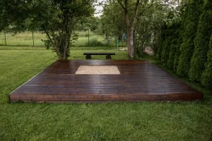 Wooden deck with a central sandpit in a lush backyard, illustrating outdoor living in unique climates.